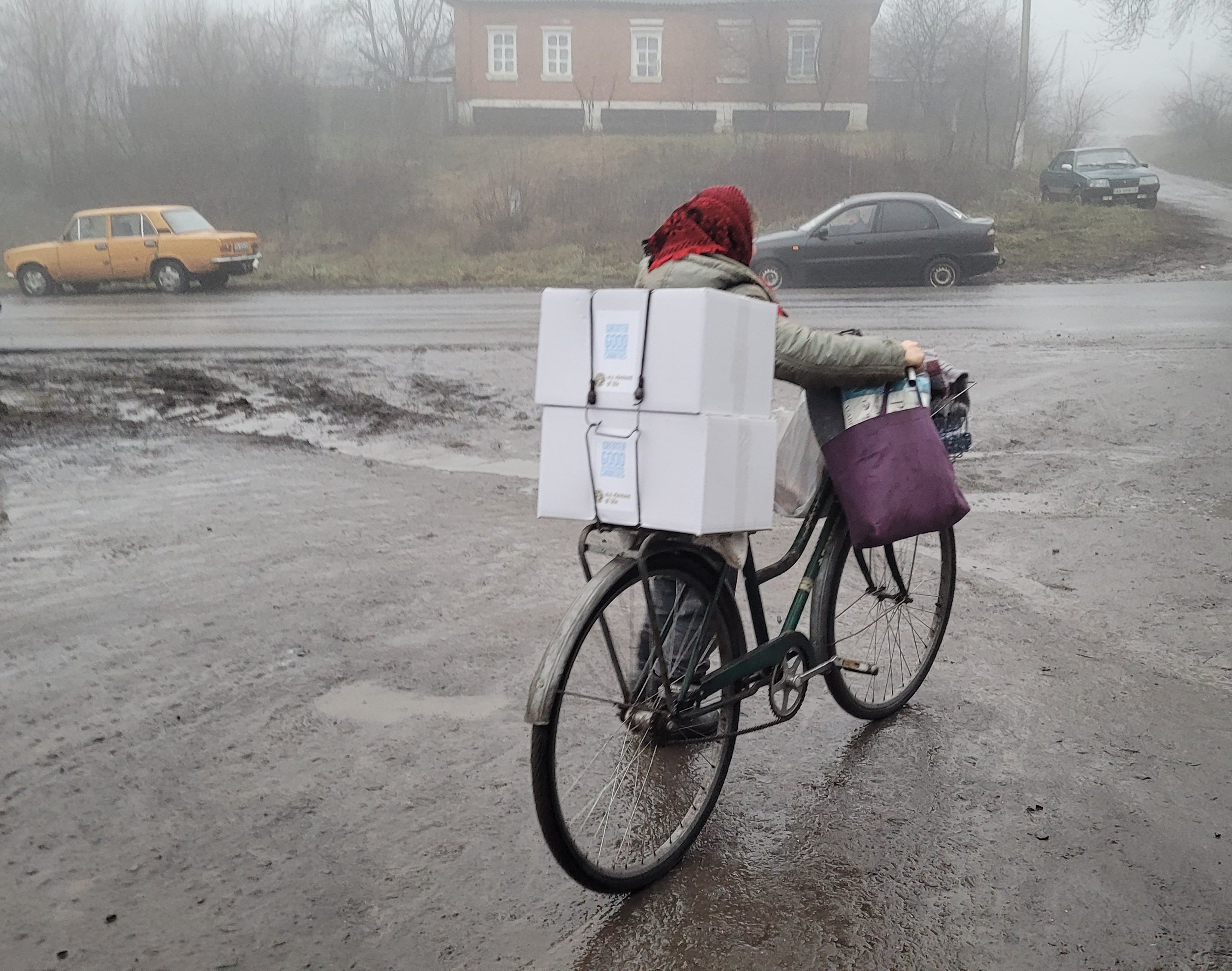 122022_Woman Bicycle Boxes_©GGC_Bilyi Kolodiaz Pizza Party + Food Boxes and Blankets Distribution_Ukraine Response 122022_Woman Bicycle Boxes_©GGC_Bilyi Kolodiaz Pizza Party + Food Boxes and Blankets Distribution_Ukraine Response